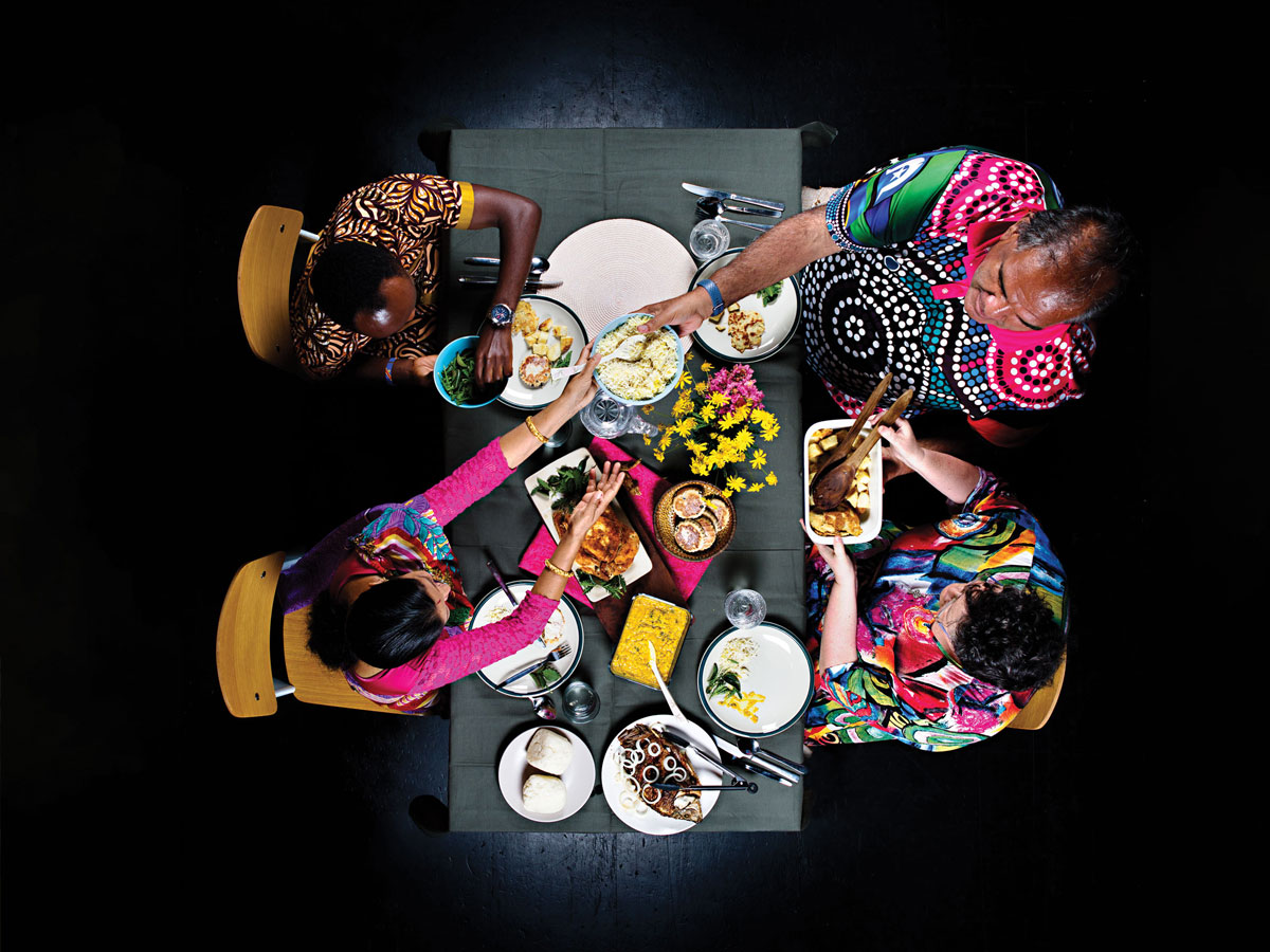 A photo from above looking down on four people eating dinner. They are sharing a meal.