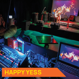 Photograph of someone performing on stage in the Happy Yess