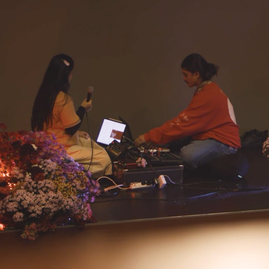 Photograph of two artists sitting down making music facing each other