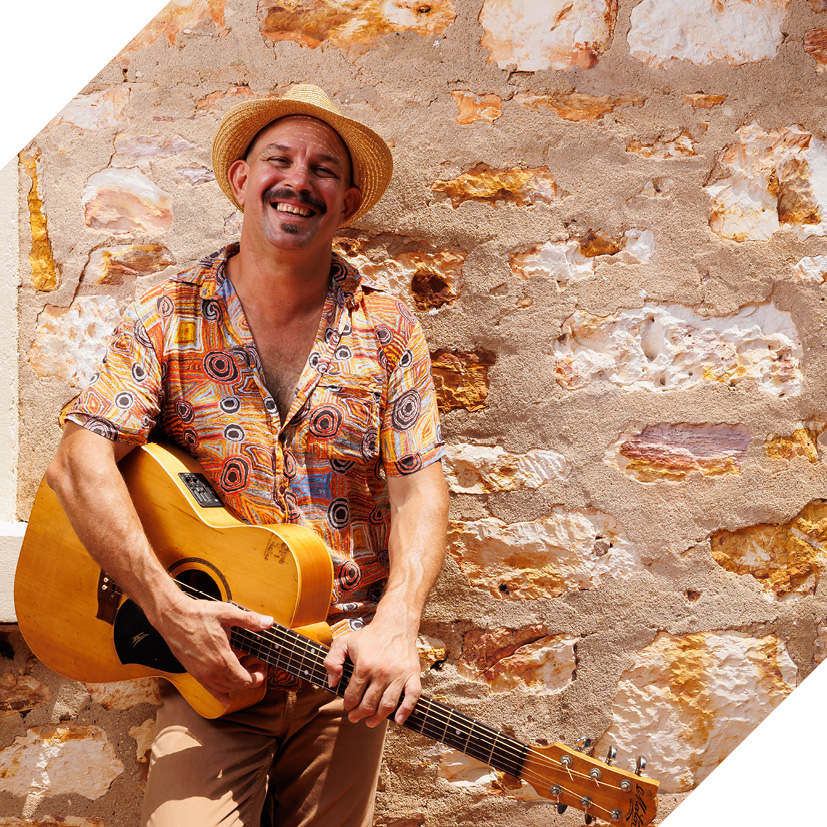 Photograph of musician David Spry holding a guitar and smiling