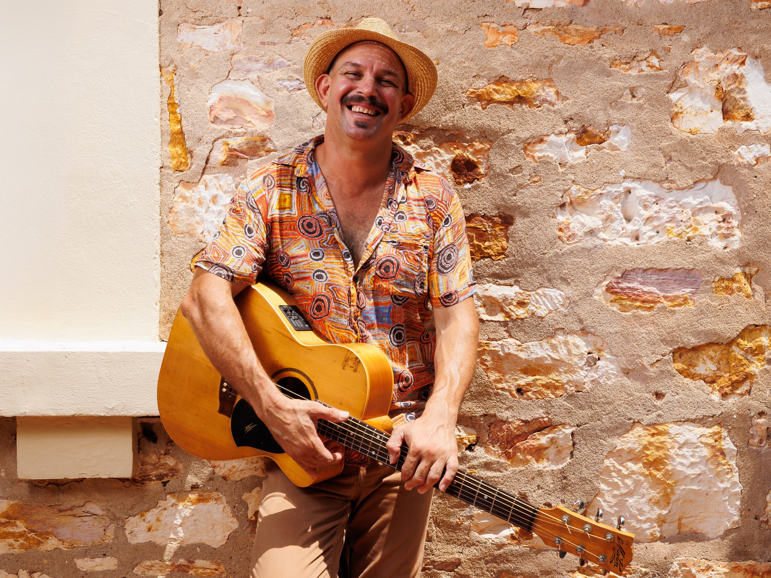 Photograph of musician David Spry holding a guitar and smiling