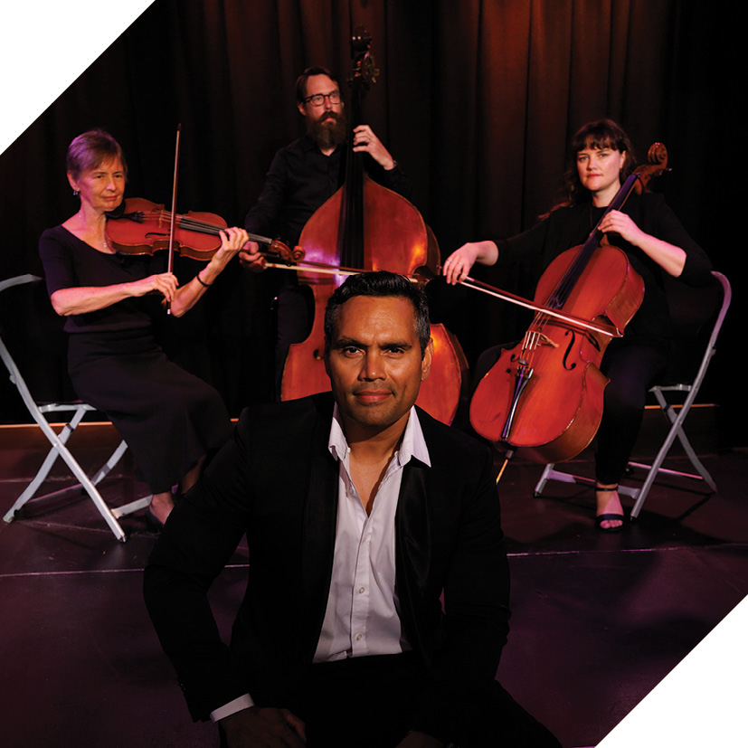 Photo of actor Rob Collins sitting in front of 3 musicians
