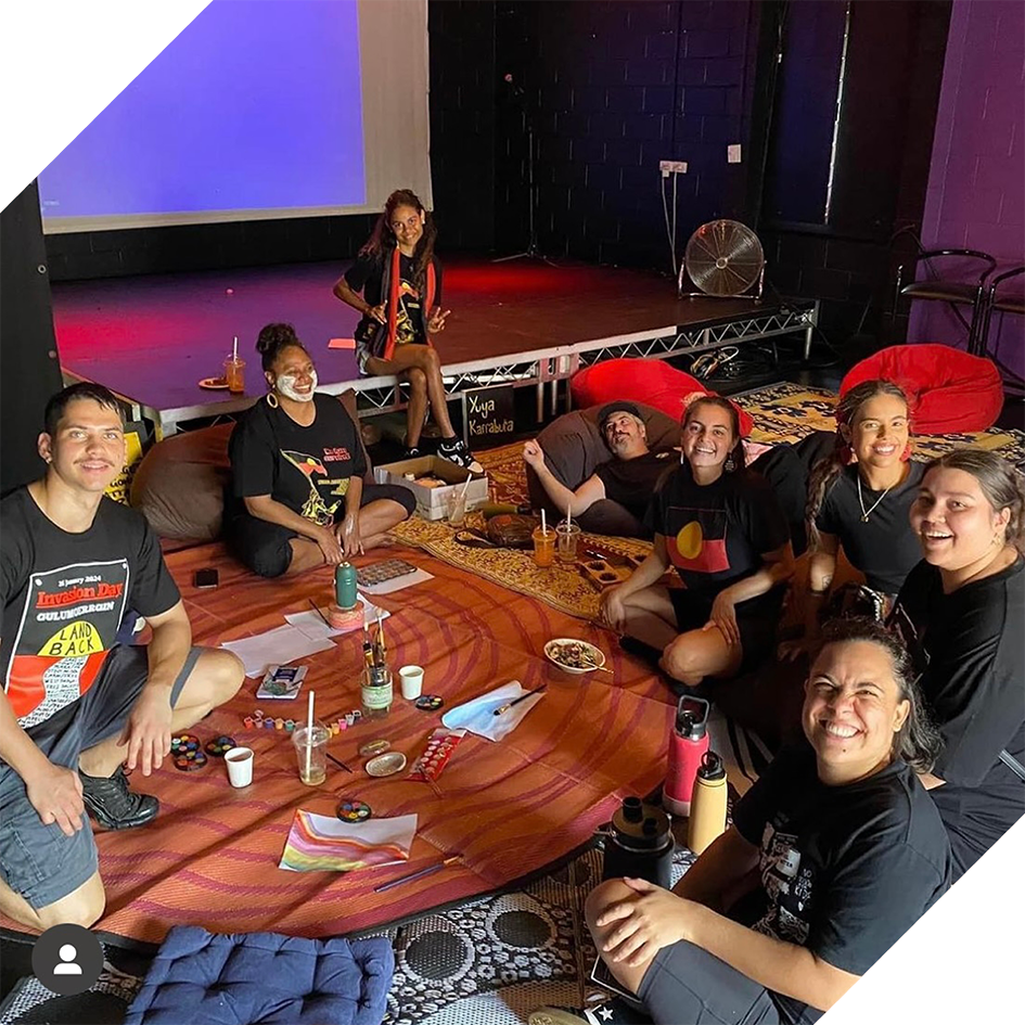 Photograph of a group of people sitting in a circle smiling at the camera.